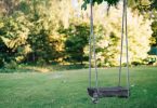 brown wooden swing on green grass field during daytime