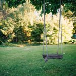 brown wooden swing on green grass field during daytime