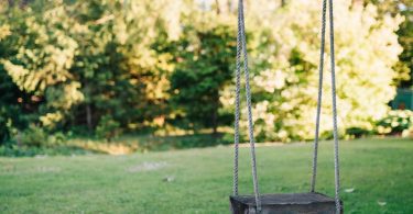 brown wooden swing on green grass field during daytime