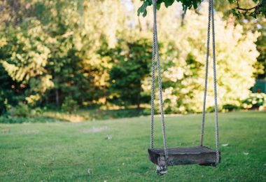 brown wooden swing on green grass field during daytime