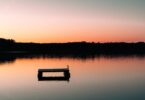 a boat floating on top of a lake at sunset