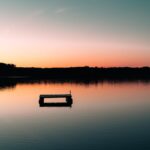 a boat floating on top of a lake at sunset