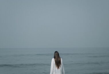 a woman standing in the ocean looking at the horizon