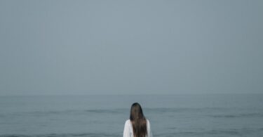 a woman standing in the ocean looking at the horizon