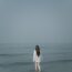 a woman standing in the ocean looking at the horizon