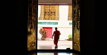 woman in red long sleeve shirt and pants walking on brown wooden floor