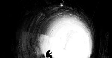 A person sitting in the middle of a dark tunnel