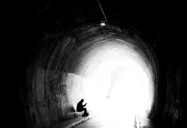 A person sitting in the middle of a dark tunnel
