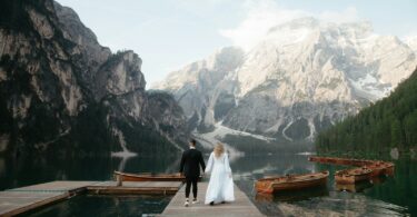 A bride and groom are standing on a dock