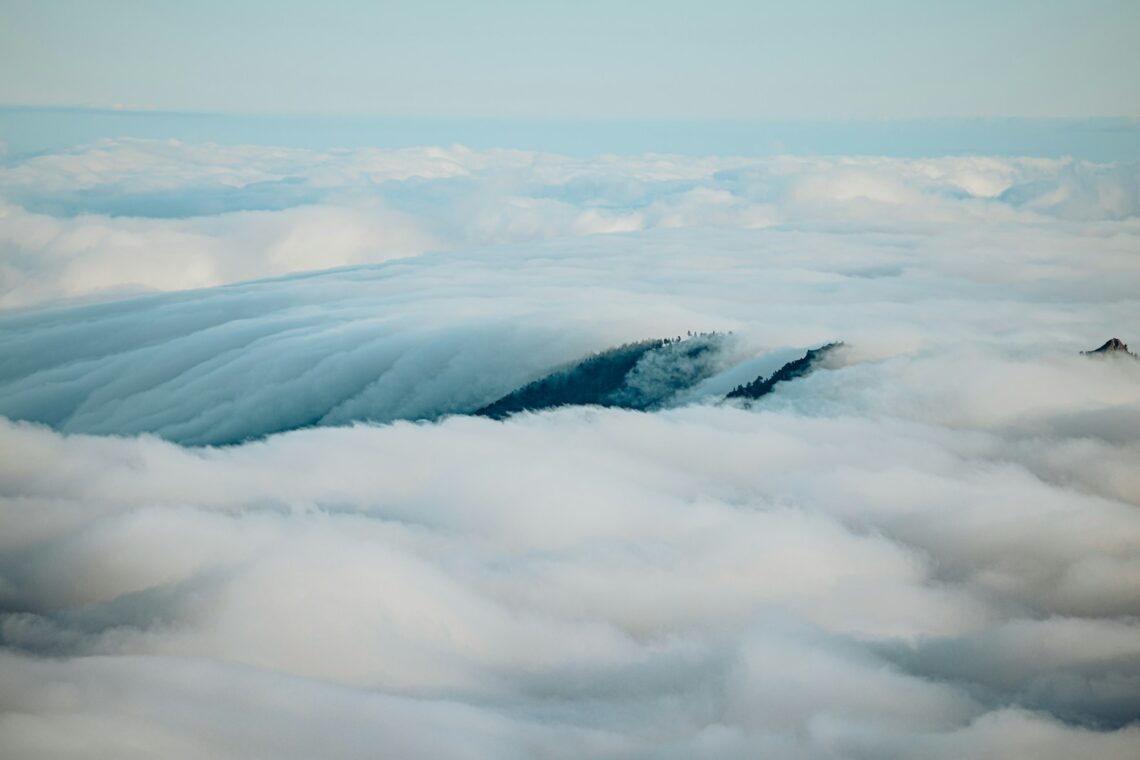 Mountains peak through a sea of fluffy clouds.