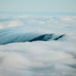 Mountains peak through a sea of fluffy clouds.