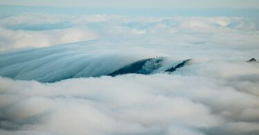 Mountains peak through a sea of fluffy clouds.