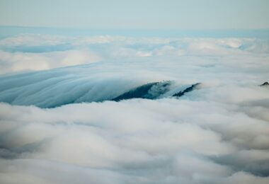 Mountains peak through a sea of fluffy clouds.
