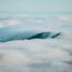 Mountains peak through a sea of fluffy clouds.