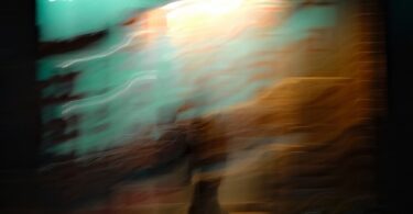 Blurred figure walking in front of a bright wall.