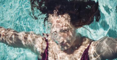 A woman swims underwater with bubbles.