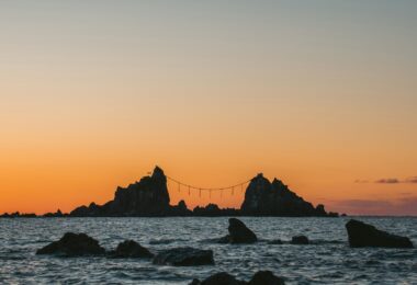 A sunrise lights up the rocks over the sea.