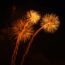 Three golden fireworks explode in the night sky.