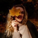 Woman holding a yellow leaf over her eye