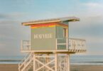 A pastel colored lifeguard station on a sandy beach.