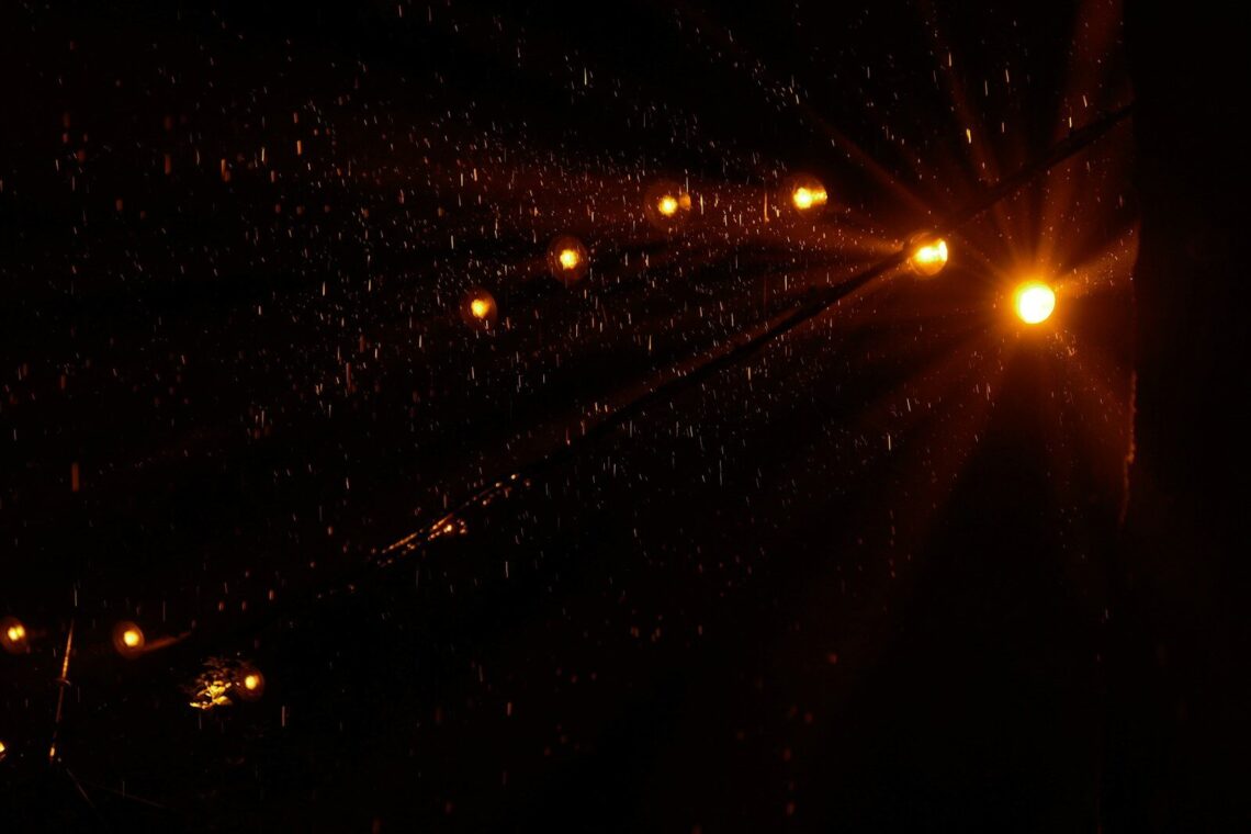 String lights glowing in the dark during a heavy rain shower at night