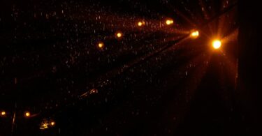 String lights glowing in the dark during a heavy rain shower at night